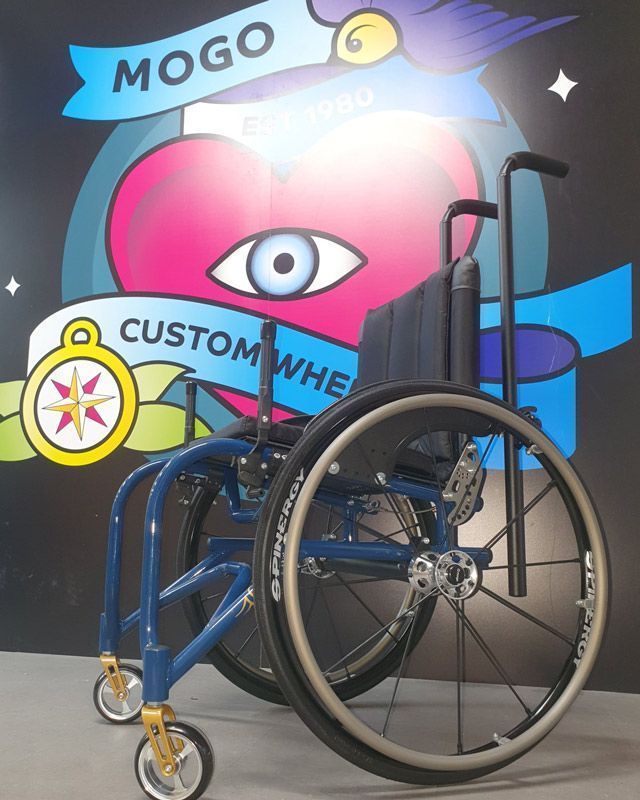 Blue custom wheelchair with black wheels in front of a heart-shaped logo.