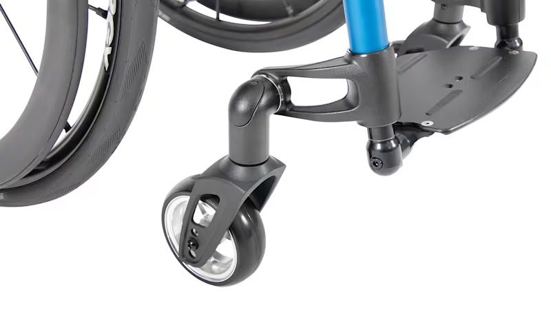 Close-up of a wheelchair's front wheel, footrest, and supporting frame. Black and blue components are visible.