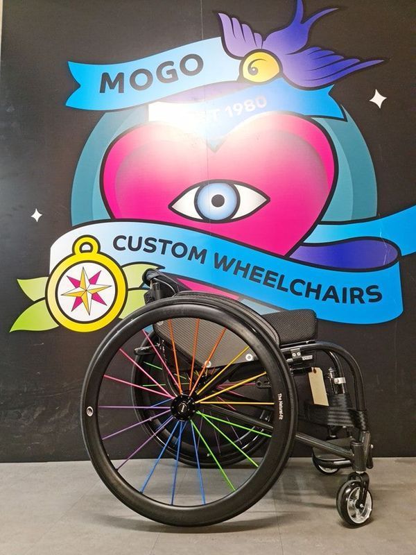 Wheelchair with rainbow spokes in front of a 