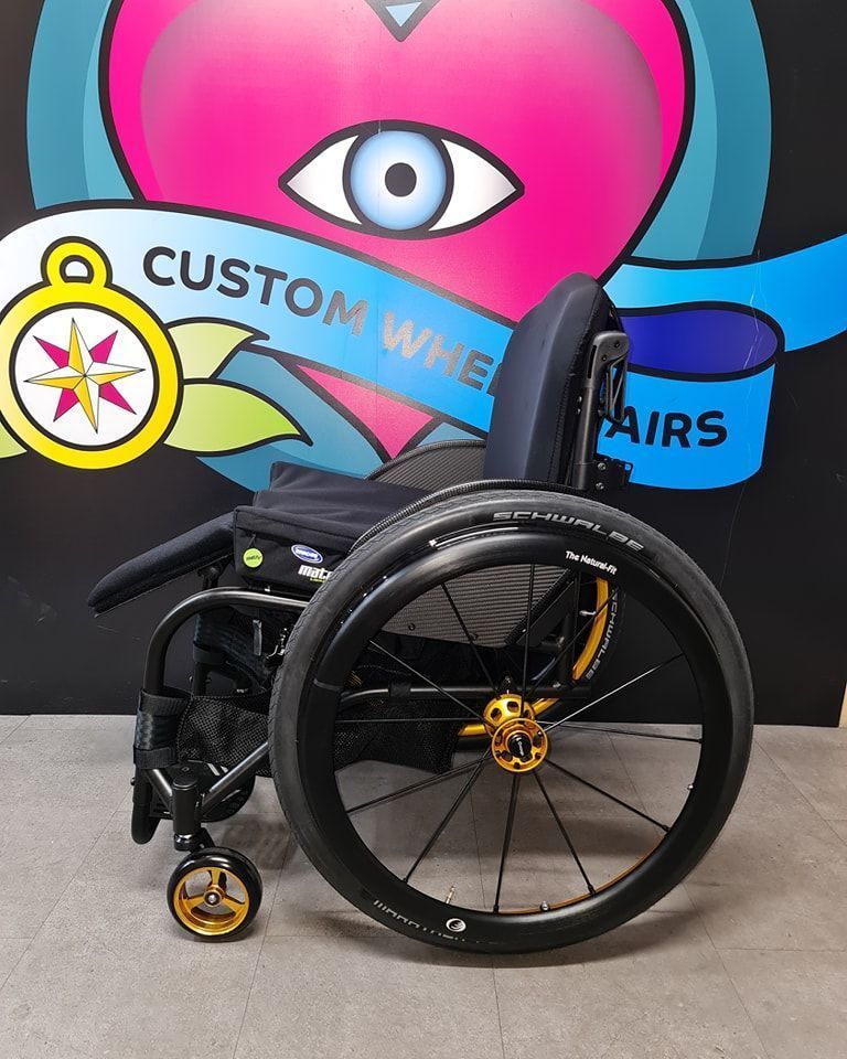 Black wheelchair with gold accents, in front of a colorful 