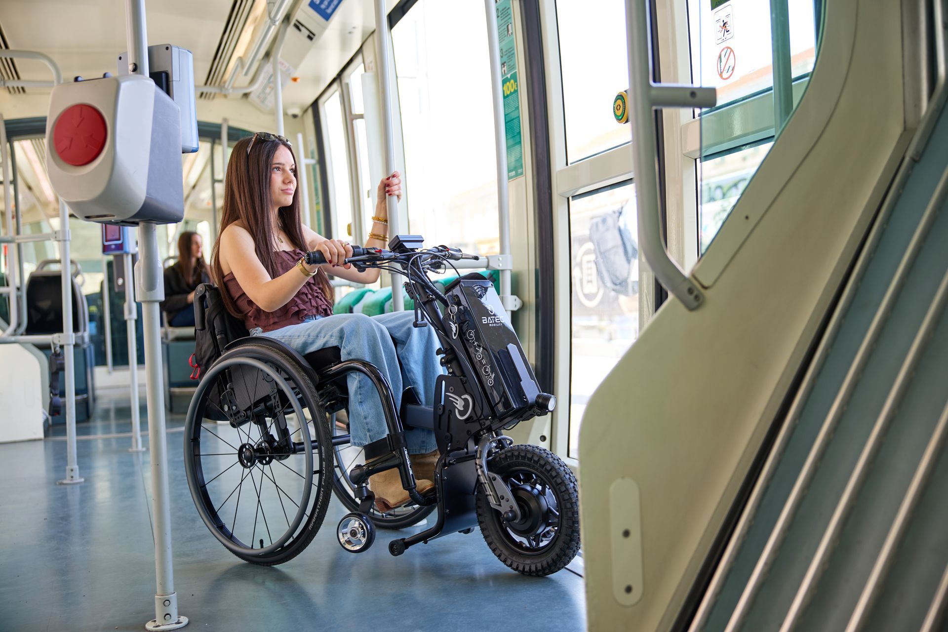 Person seated on a wheelchair-bike riding indoors through a transit station corridor