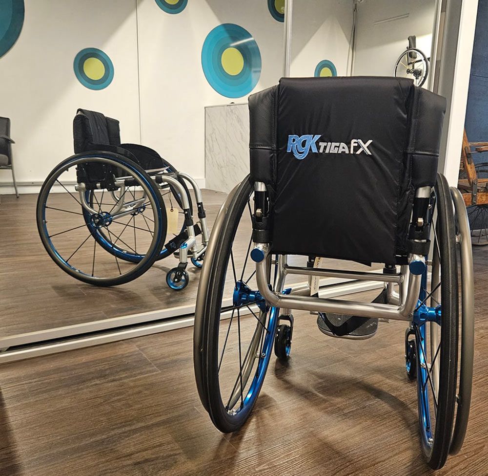 Wheelchair with blue accents, in front of a mirror, with colorful wall decor in a brightly lit room.