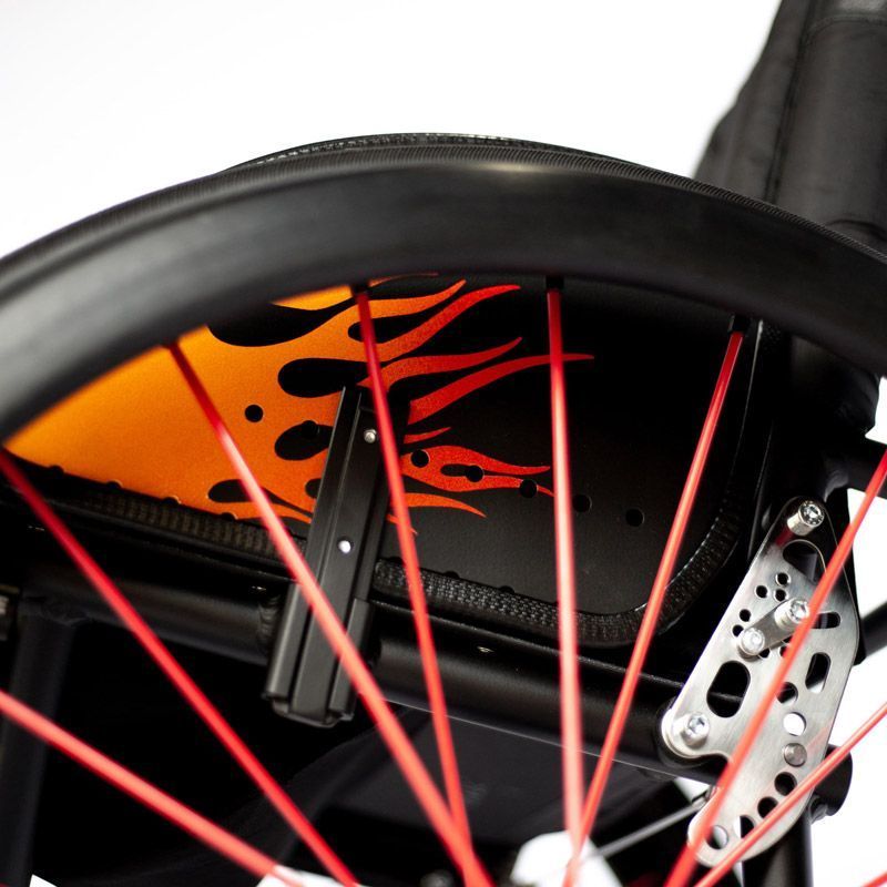 Close-up of a wheelchair with red spokes and a flame design on the side.