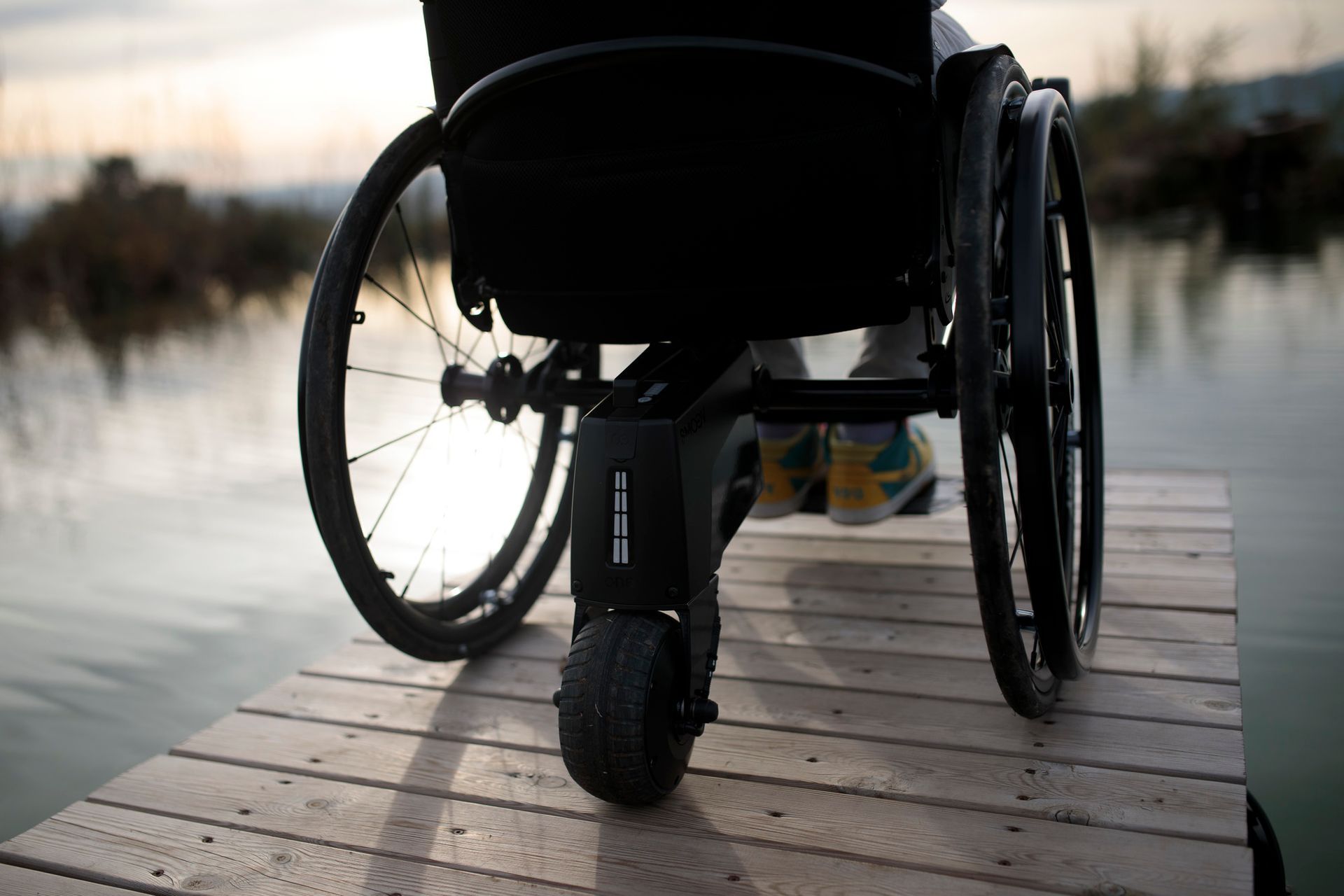 Wheelchair on a wooden dock overlooking water.