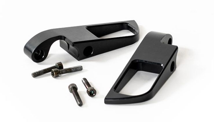 Black motorcycle foot peg brackets and screws on a white background.