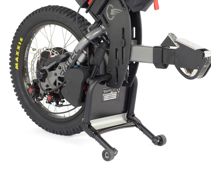Rear wheel of a black electric folding bike with fat tire and rear cargo rack on white background