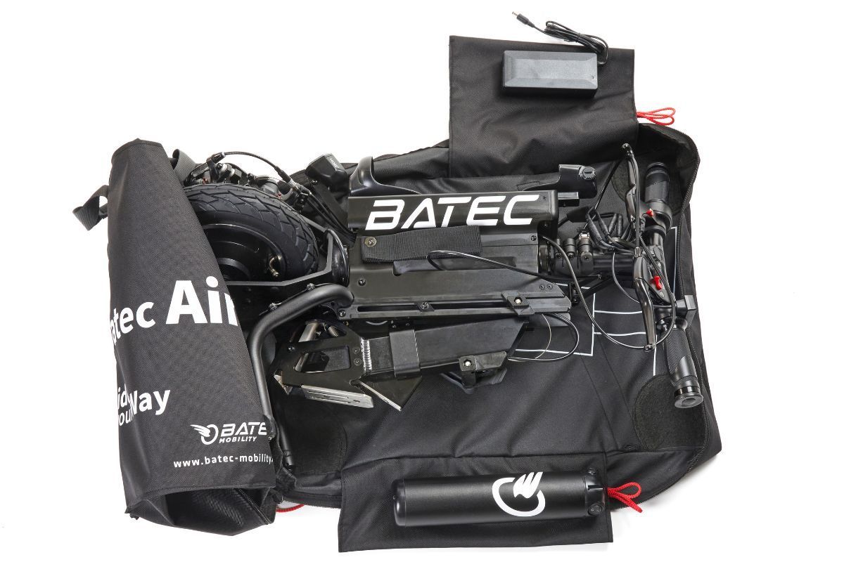 Black Batec Air handbike, folded inside a carrying bag. Includes wheel, battery, and controls.