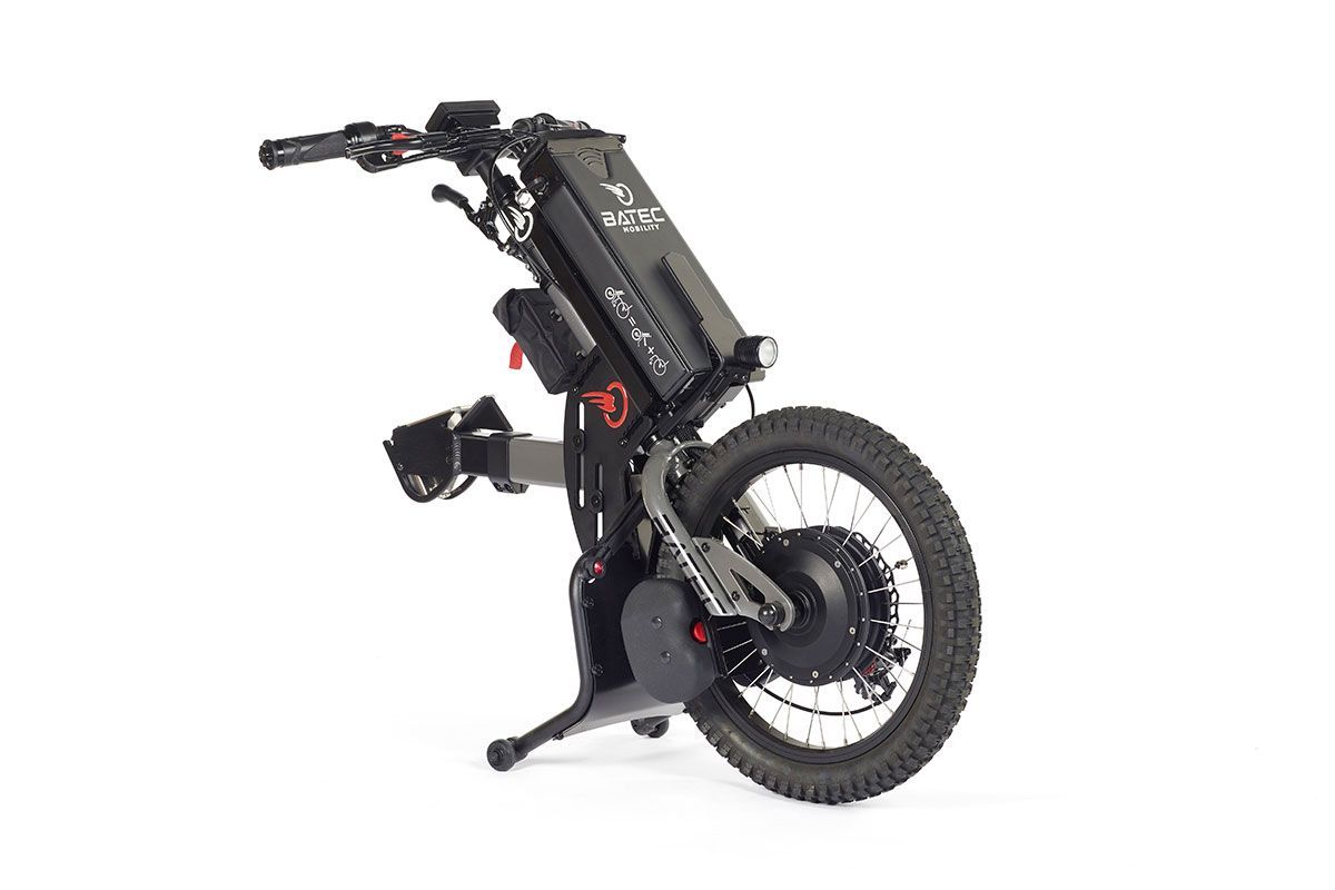 Black motorized wheelchair with large off-road tire. Features include handlebars, footrests, and battery pack.