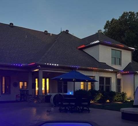 Backyard patio at dusk with string lights, blue umbrella, and a house lit warm from inside
