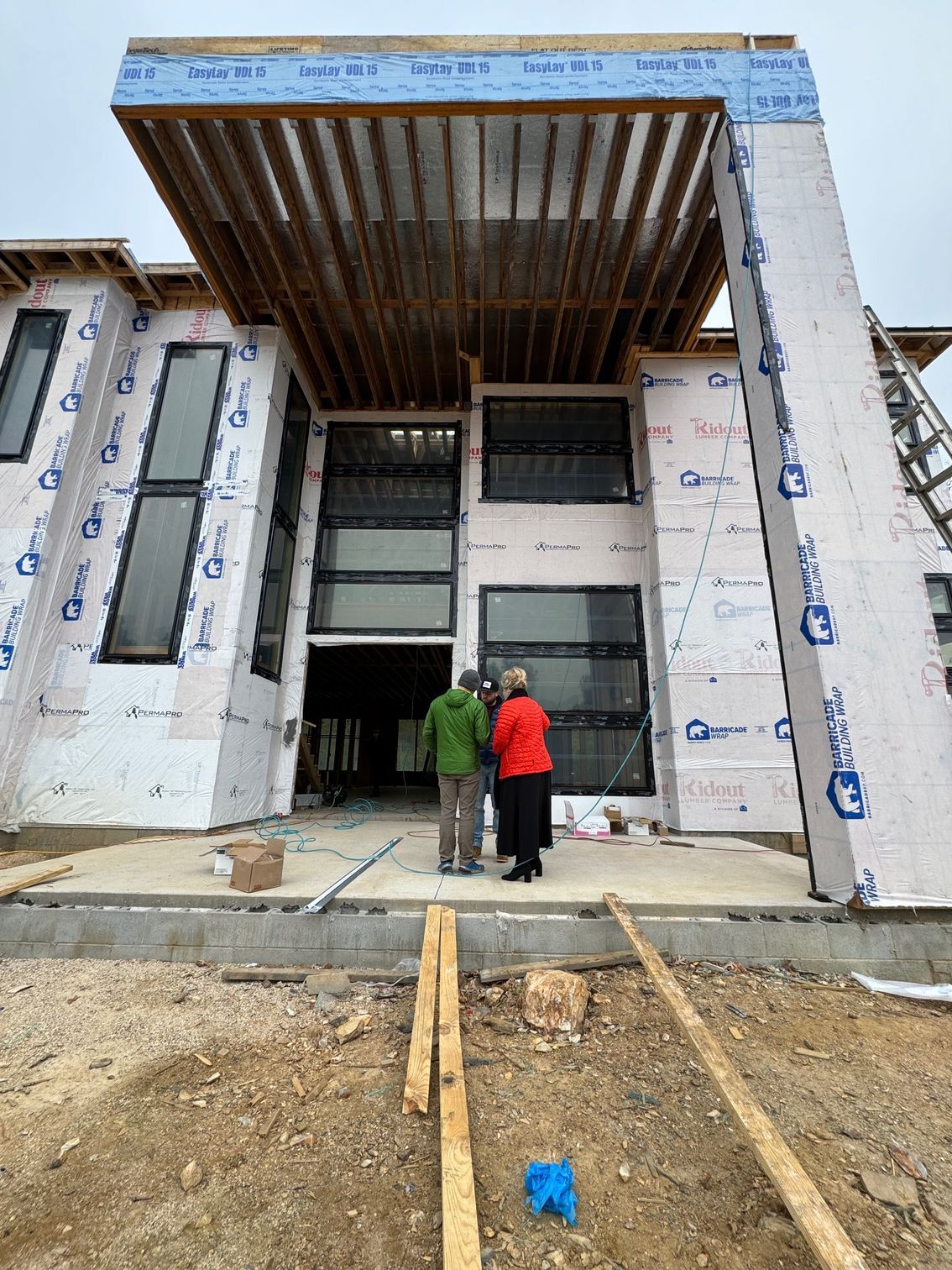 Two workers stand at the entrance of a modern building under construction.