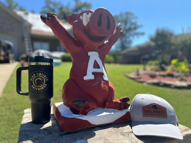 Painted red mascot statue with a white “A,” flanked by two drink cups on a sunny outdoor table.