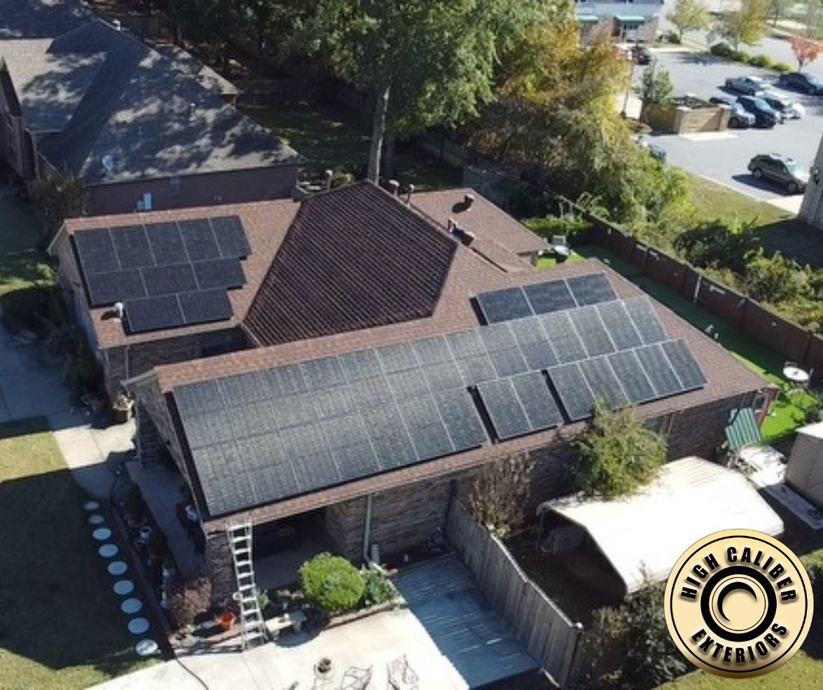 Aerial view of a house with solar panels on multiple roofs and a backyard patio.