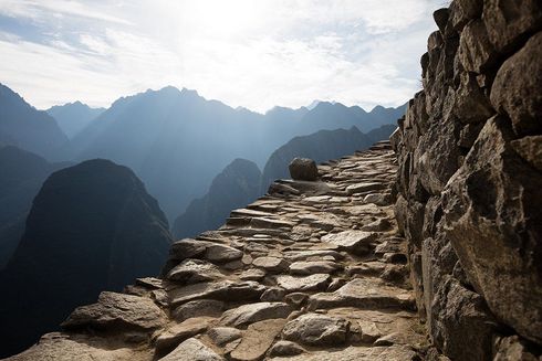 Rocky mountain path along a steep cliff with distant blue peaks in morning haze