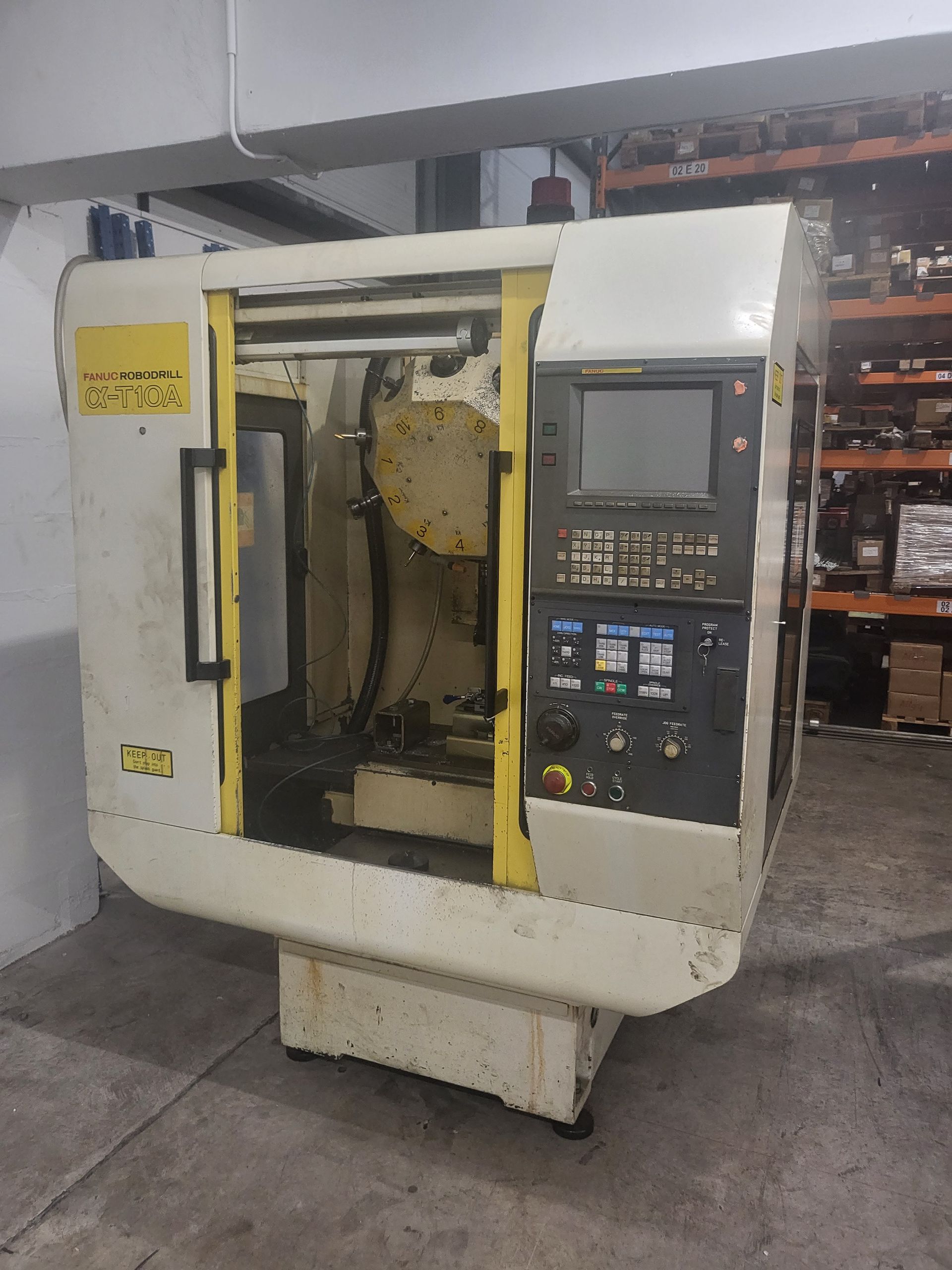 A machine with a yellow door is sitting in a warehouse.