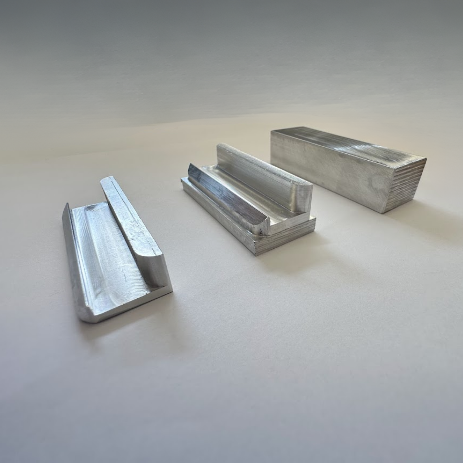 Three pieces of metal are sitting on a white surface.