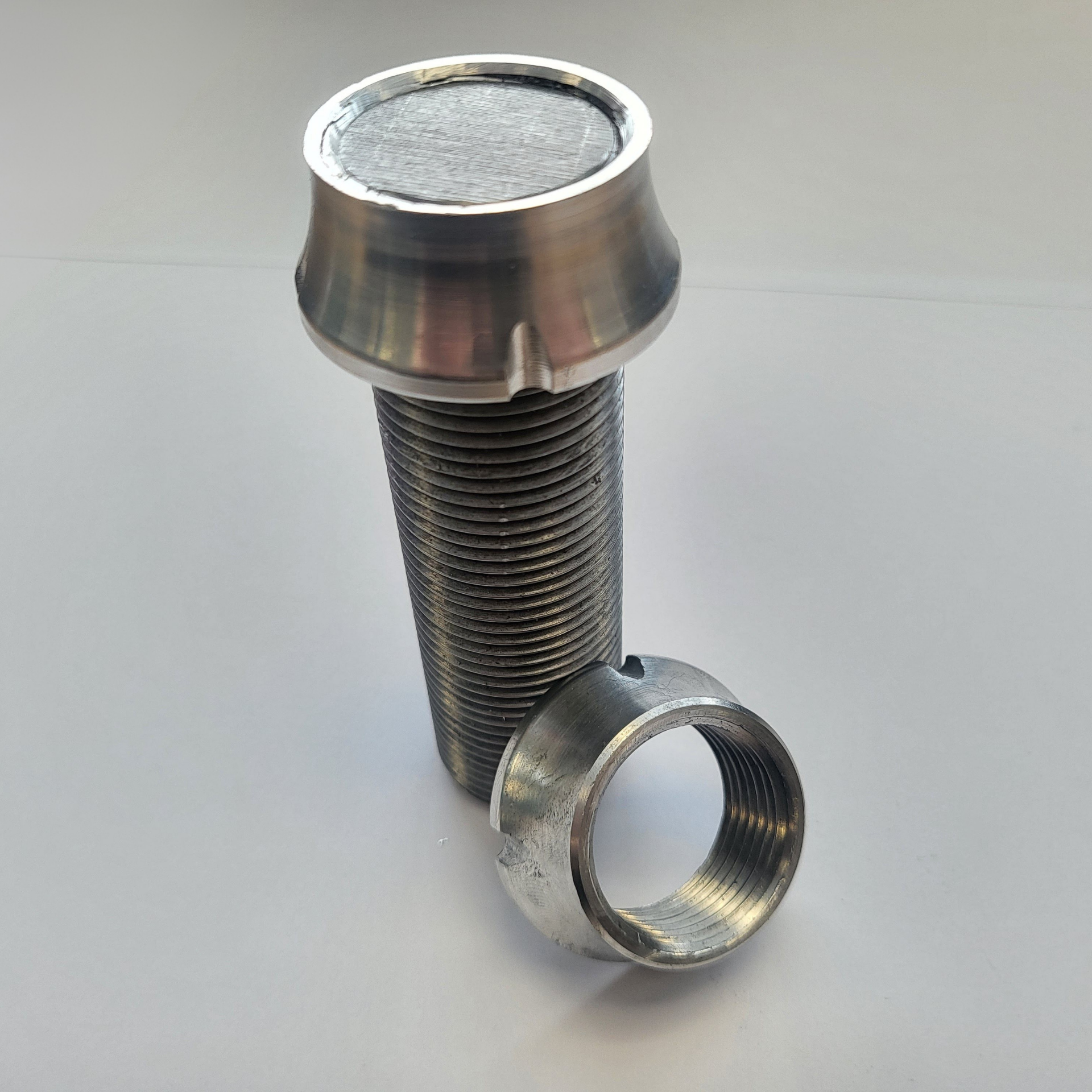 A screw and a nut are sitting on a white surface