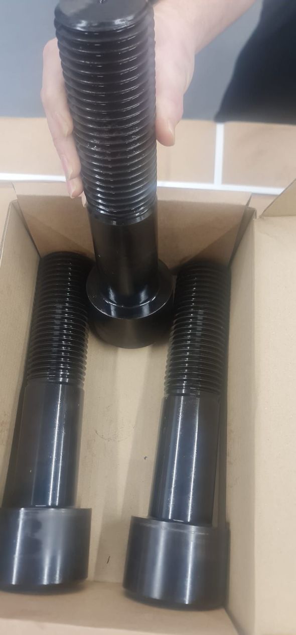 A person is holding a pair of screws in a box.