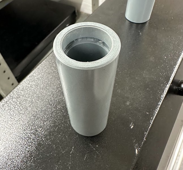 A gray plastic tube with a hole in the middle is sitting on a table.
