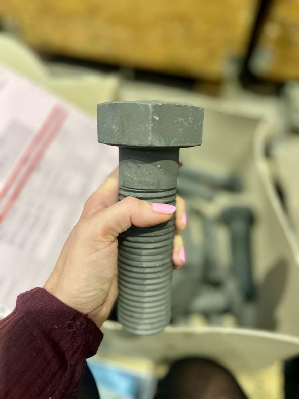A person is holding a large gray bolt in their hand.