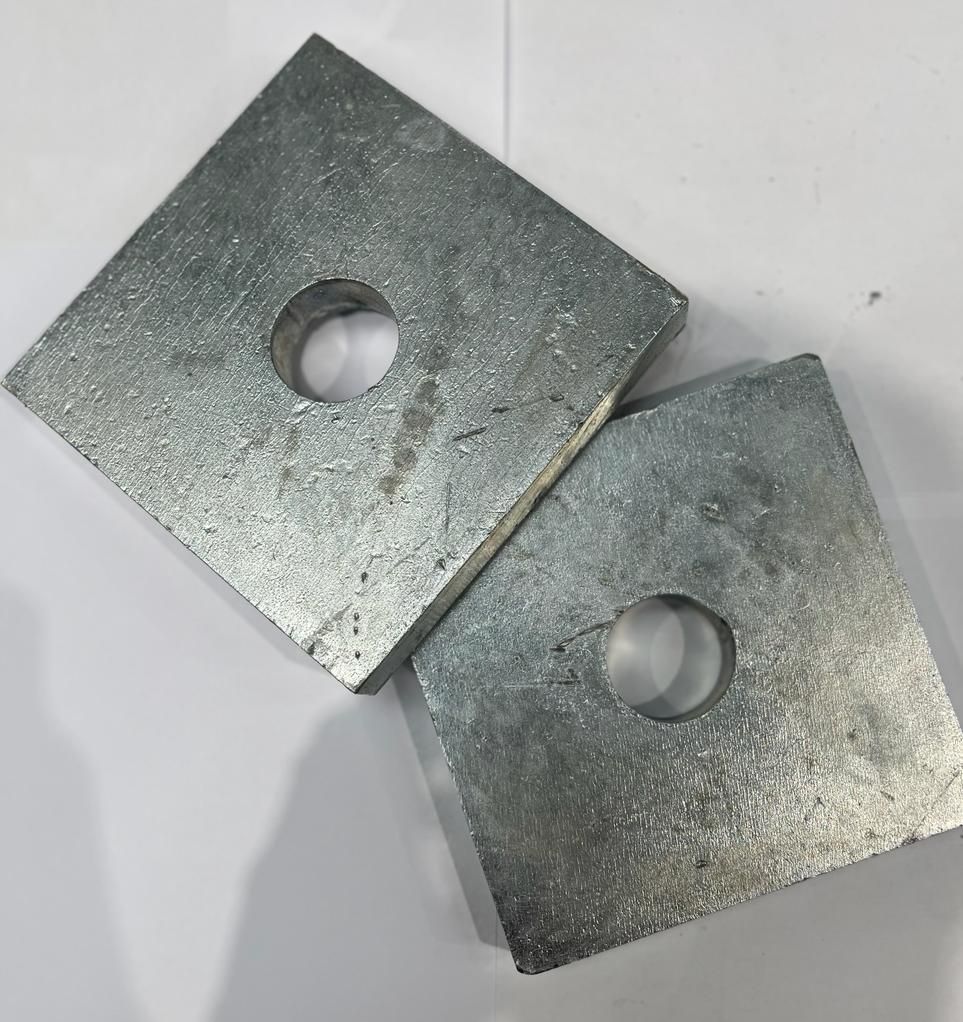 Two square metal plates with holes in them are stacked on top of each other on a white surface.