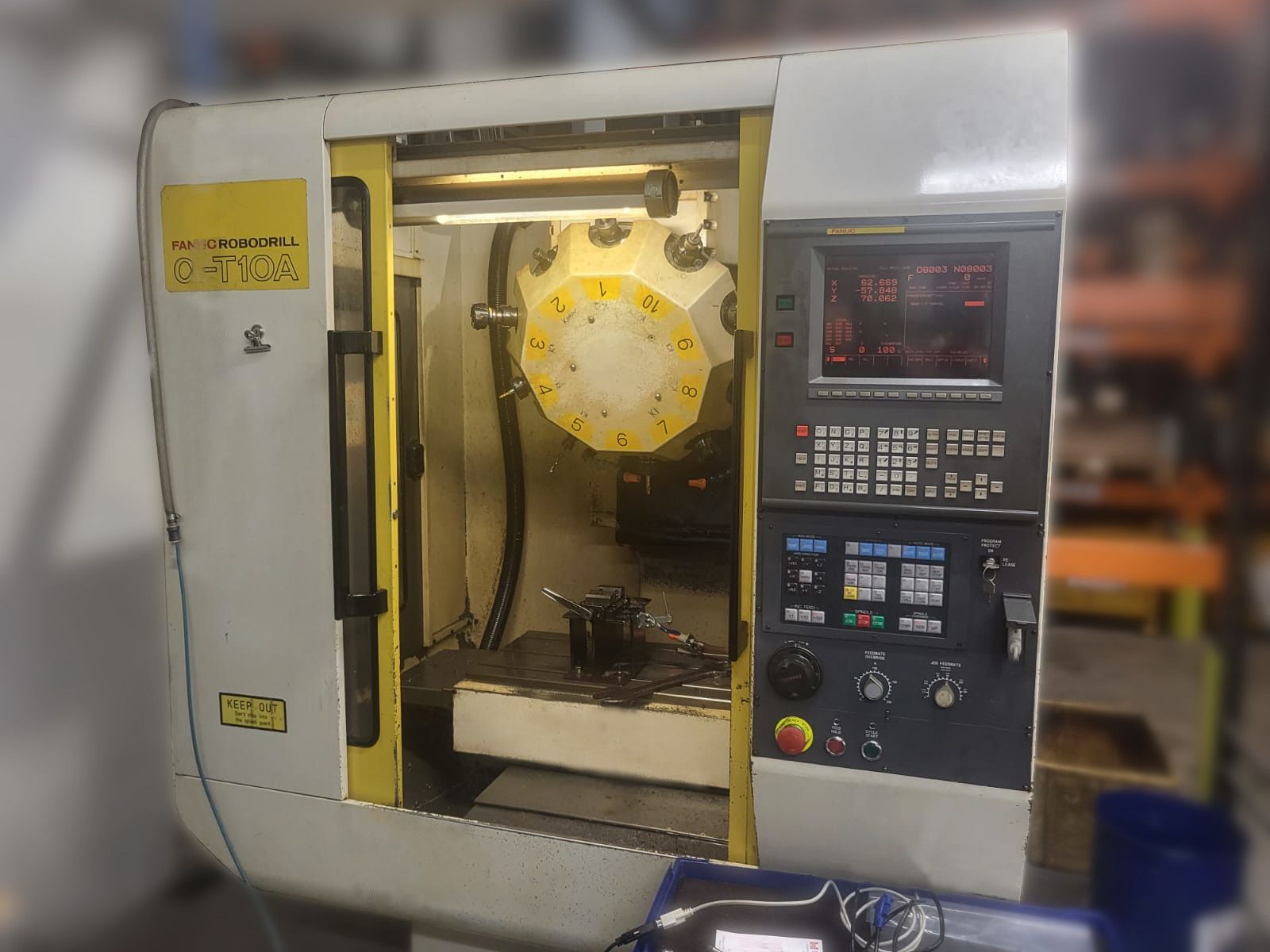 A machine with a yellow door is sitting in a warehouse.