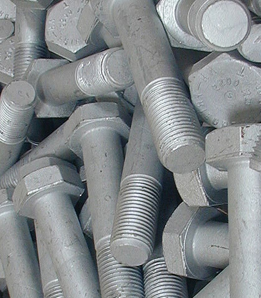Pile of galvanized steel bolts with hexagonal heads.