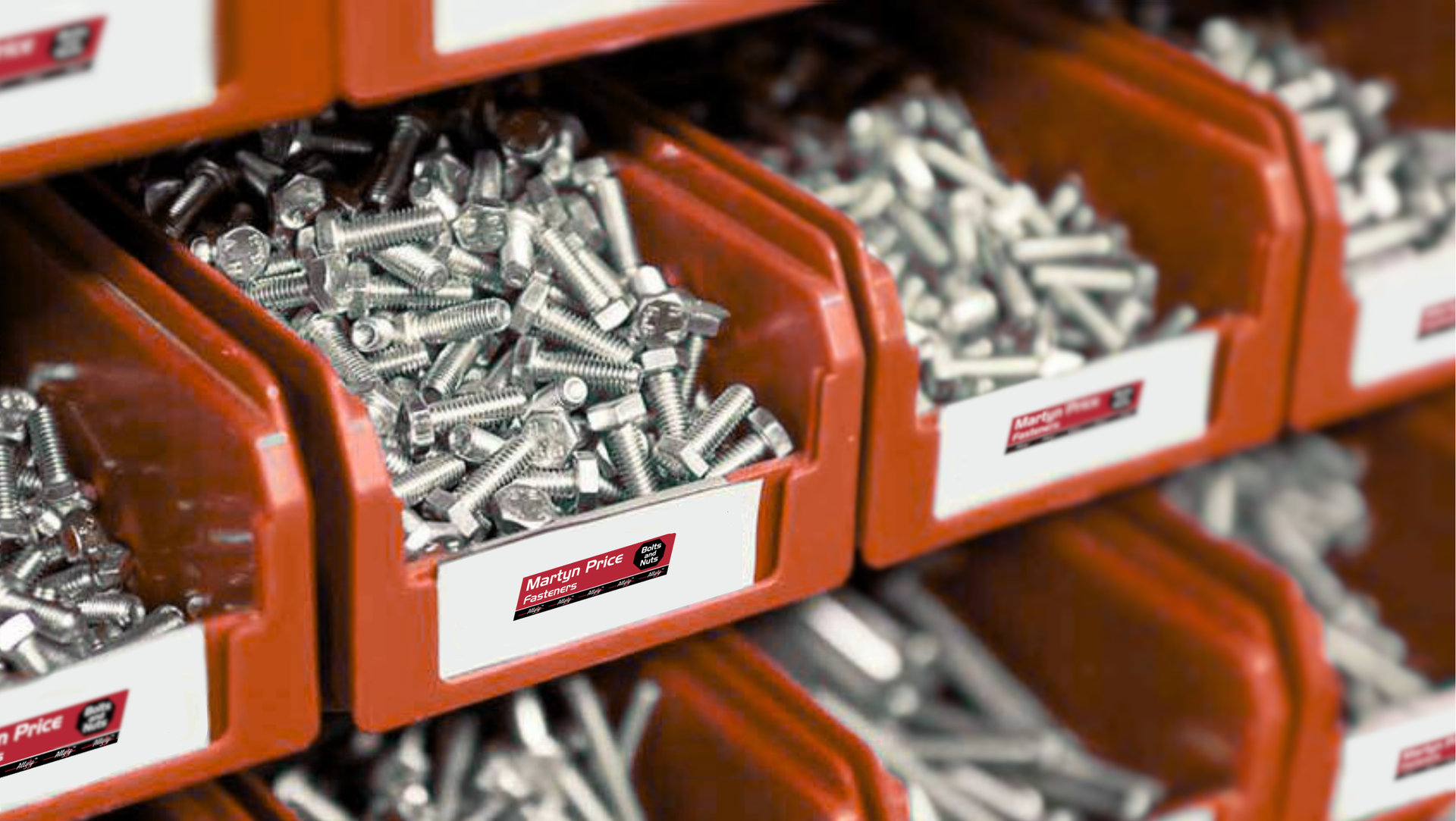A shelf filled with red bins filled with nuts and bolts.