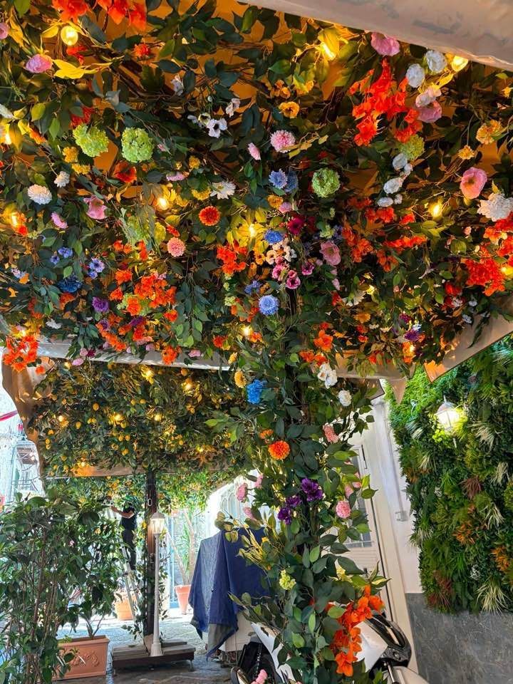 Arco da giardino ricoperto di fiori con boccioli colorati e vegetazione sopra un sentiero