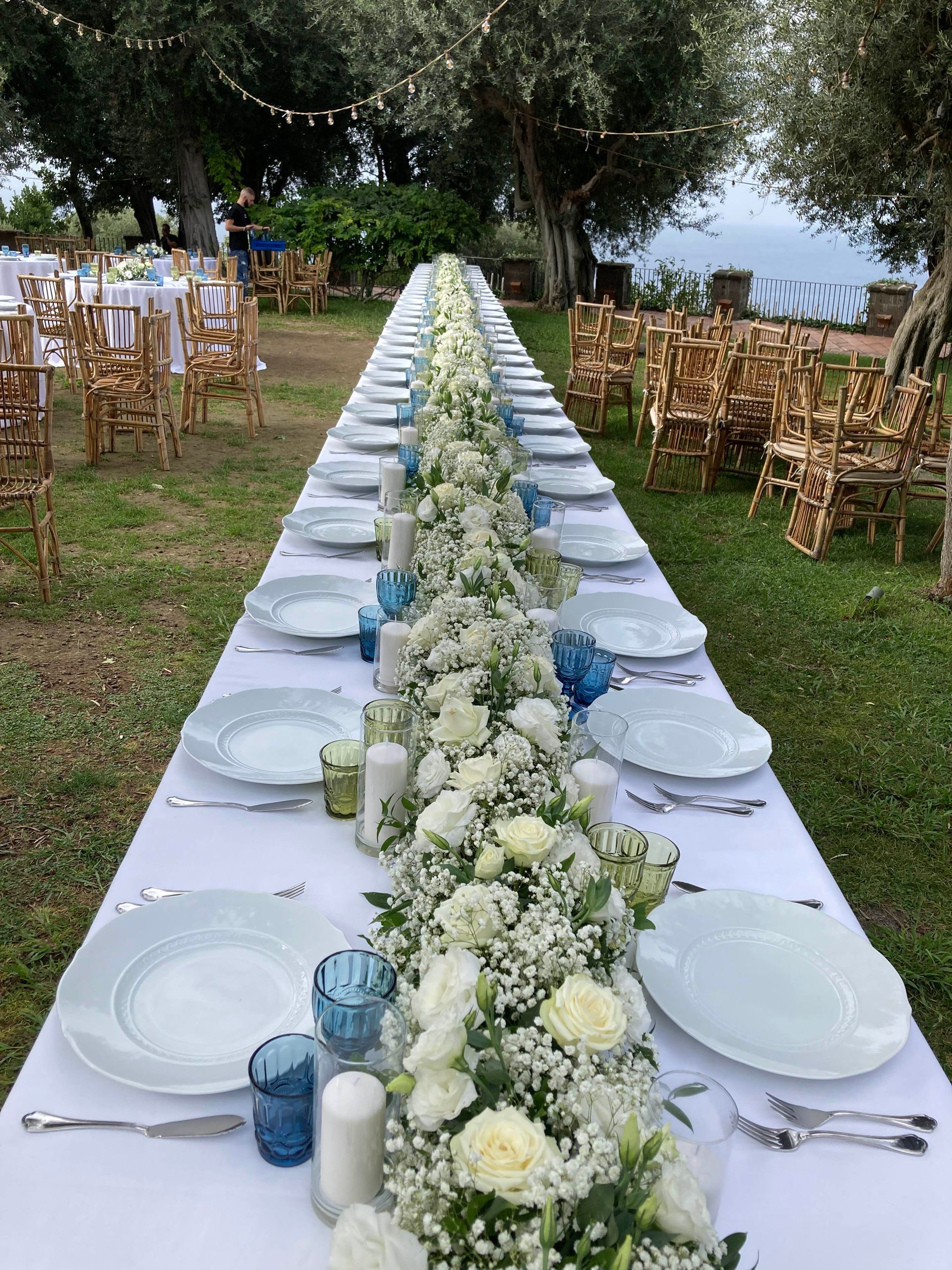 Tavolo lunghissimo con fiori al centro per matrimonio