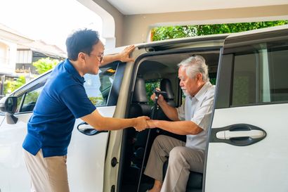 Man helping elderly passenger into a white van through the open side door Man helping elderly passenger into a white van through the open side door