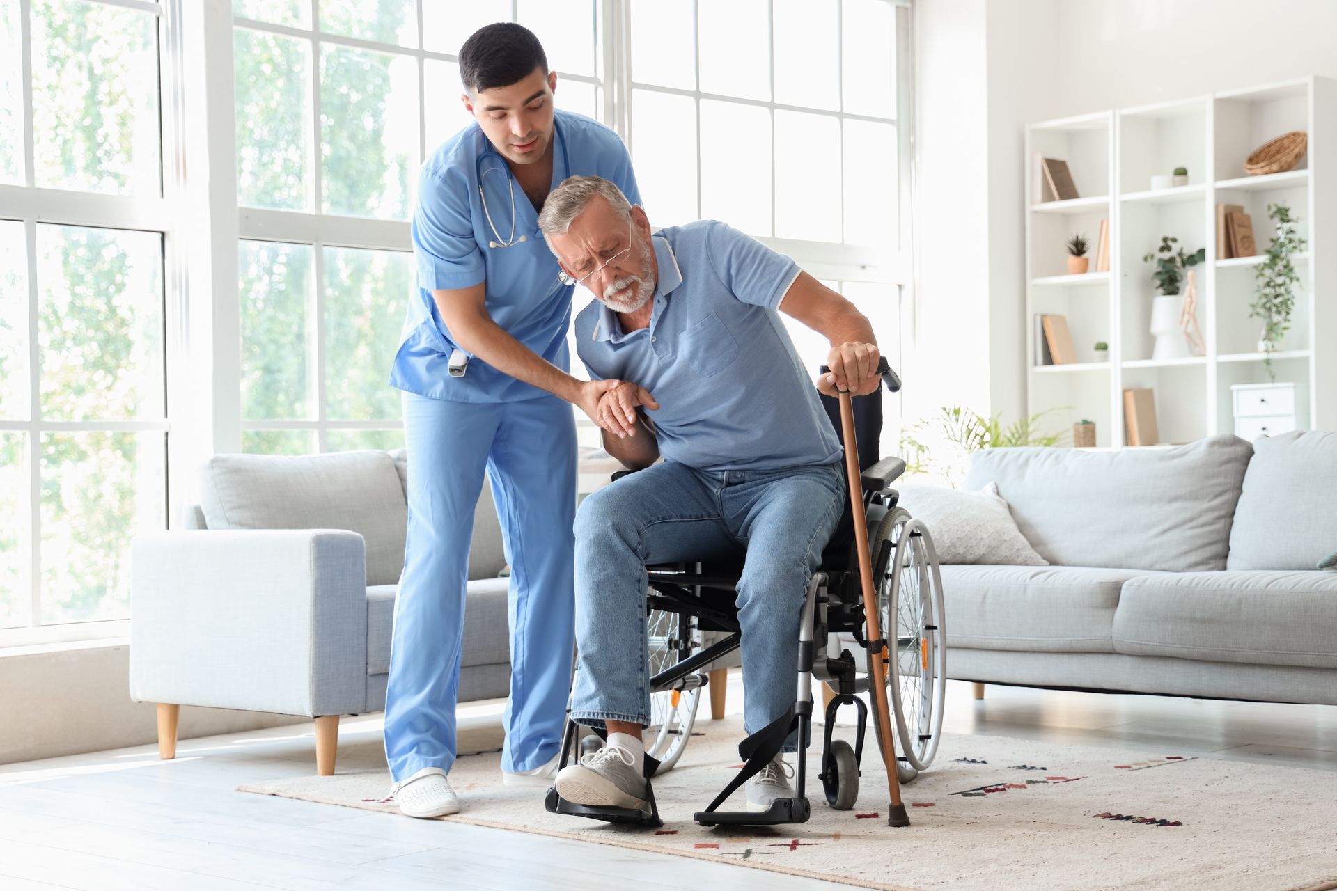 Caregiver helping an elderly man rise from a wheelchair in a bright living room Caregiver helping an elderly man rise from a wheelchair in a bright living room
