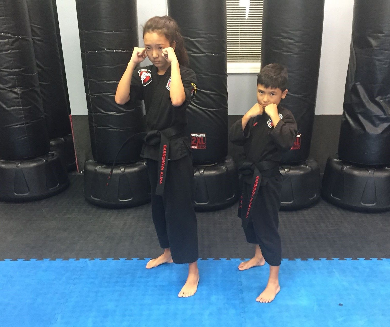 A boy and a girl are practicing martial arts in a gym.