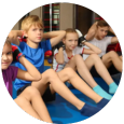 A group of children are sitting on the floor doing exercises.
