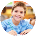 A young boy is sitting at a table with a pencil in his hand.