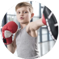 A young boy is wearing boxing gloves in a gym.