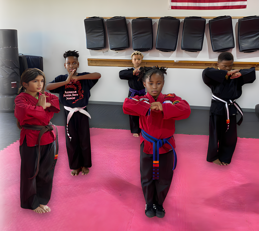 A group of kids are practicing martial arts on a pink mat
