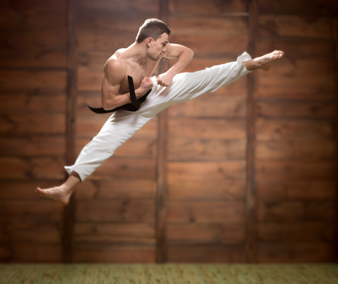 A man is practicing karate in front of a wooden wall.