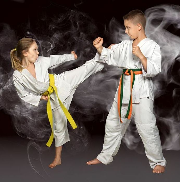 A boy and a girl are practicing karate in a dark room.