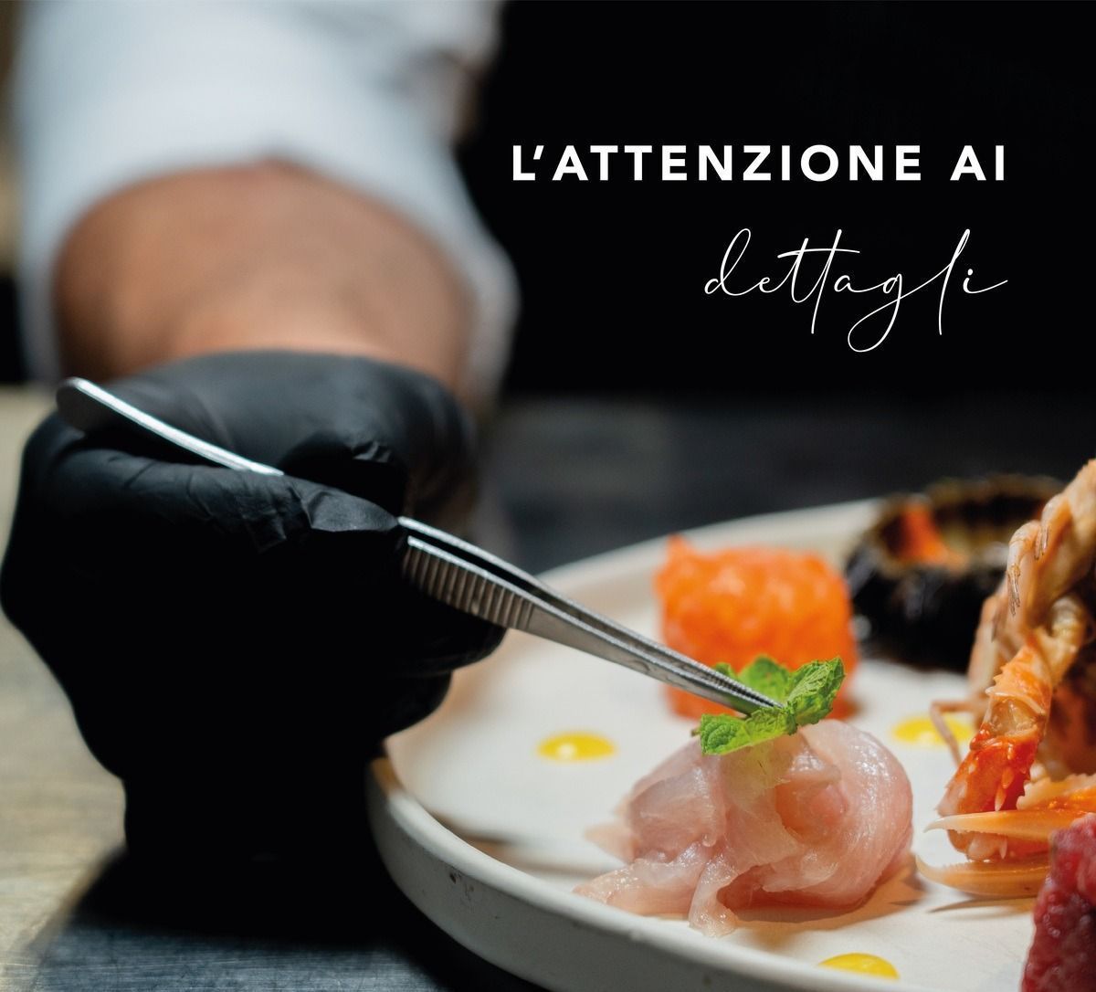 Una persona che indossa guanti neri tiene un paio di pinzette sopra un piatto di cibo