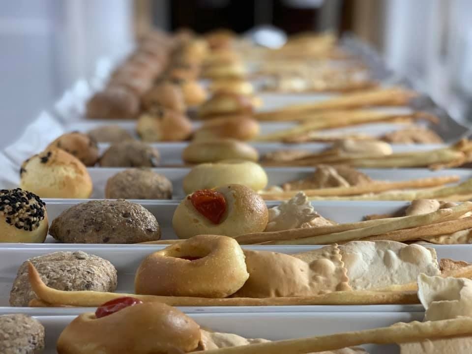 Una fila di vassoi pieni di diversi tipi di pane e pasticcini.