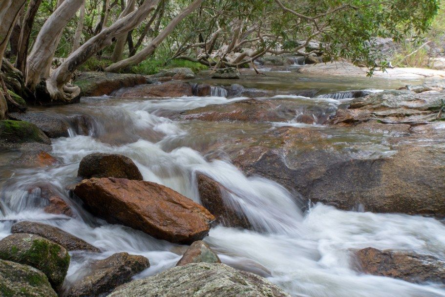 A Flowing River Cascades Over Rocks, With Trees Overhead — All Grind & Coat in Mareeba, QLD