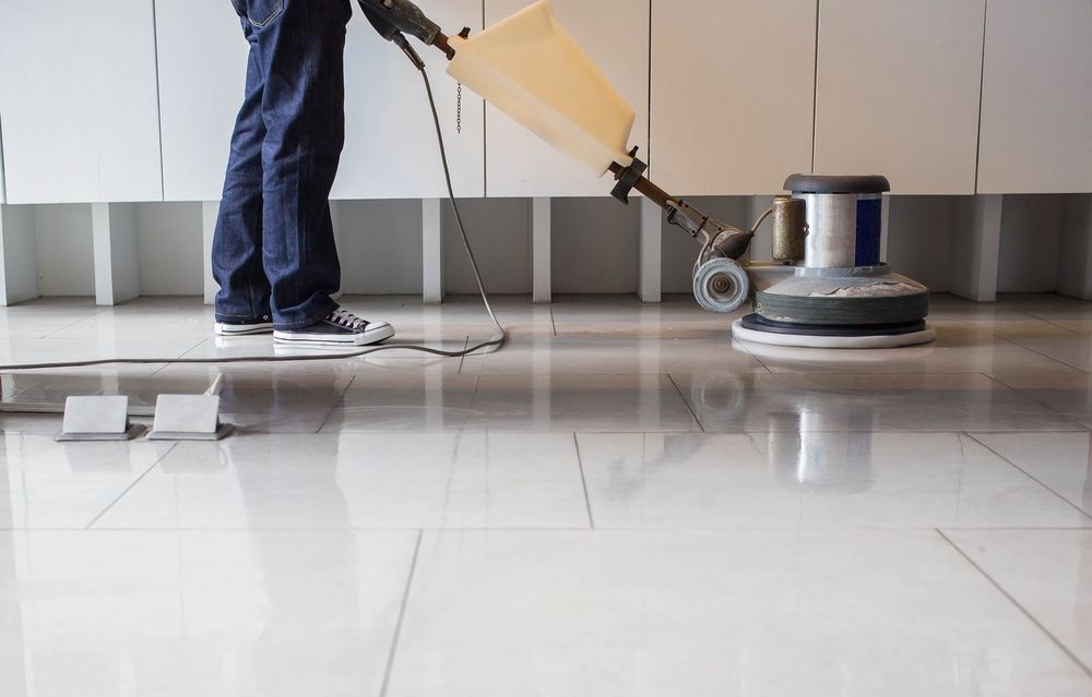 Person Using Floor Buffer to Clean Shiny White Tile Floor — All Grind & Coat in Tablelands, QLD