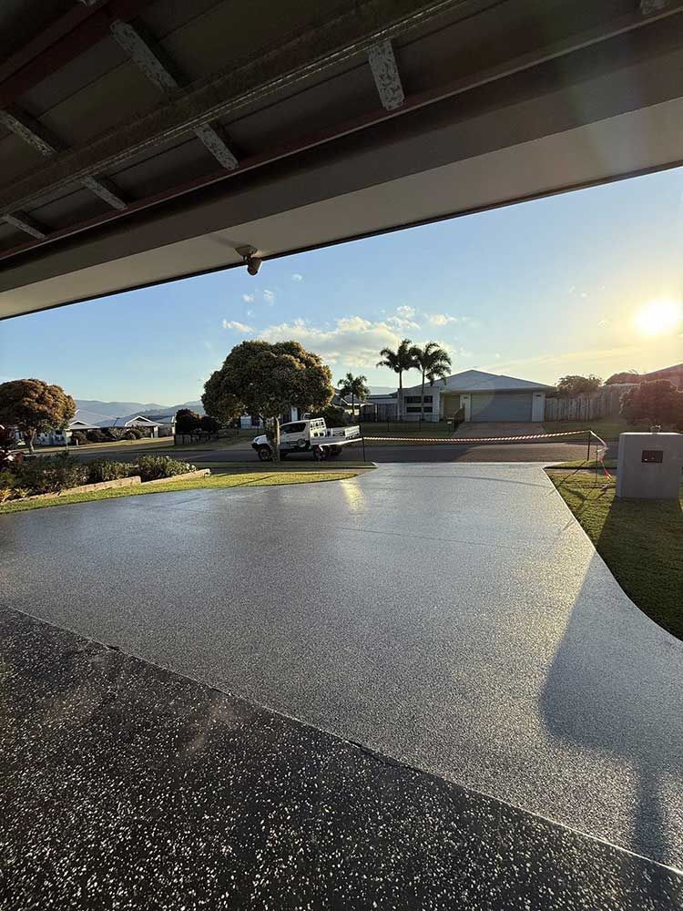 A Driveway With a Grey Flecked Concrete Finish View From Under a Garage — All Grind & Coat in Cairns, QLD