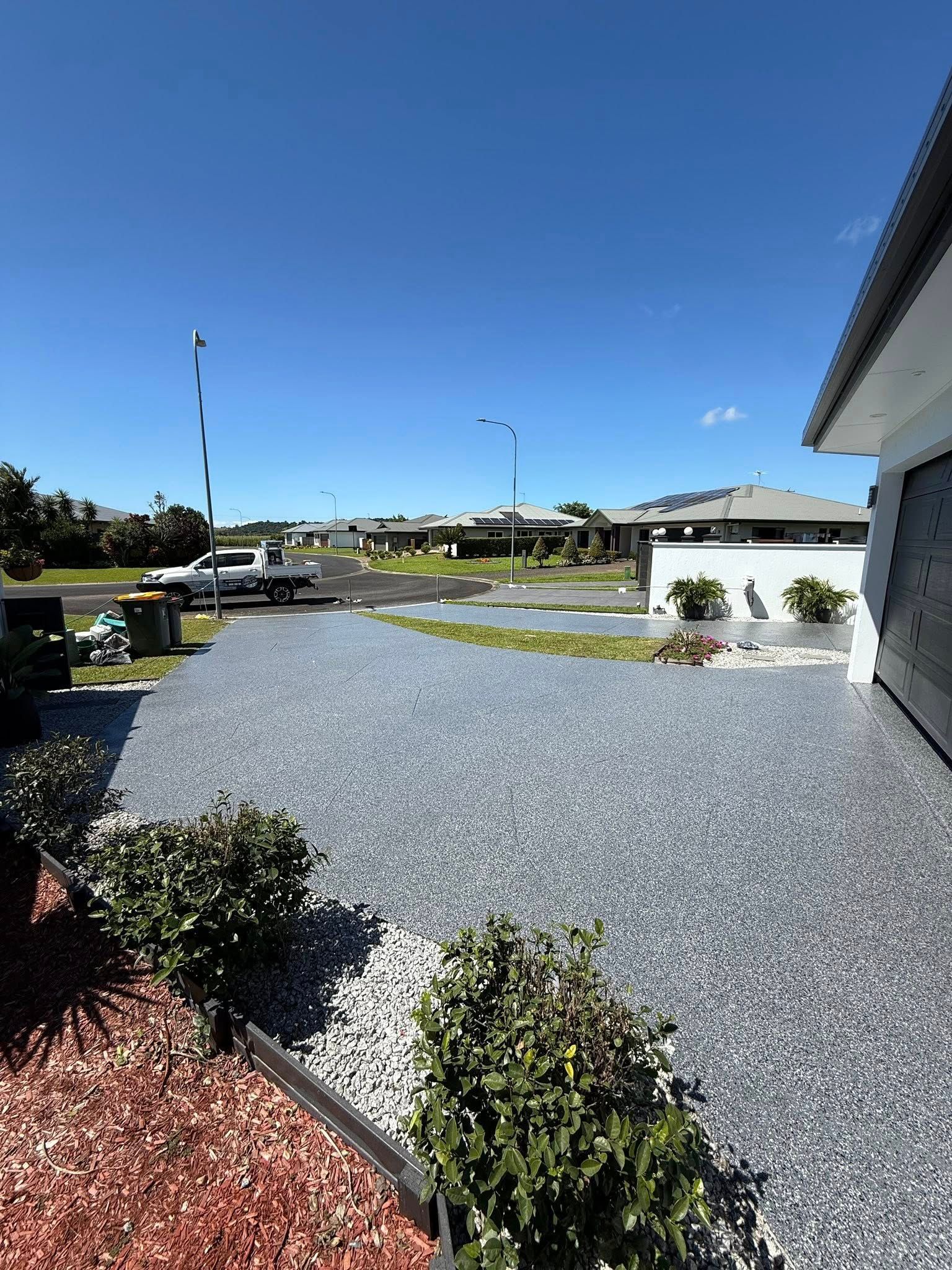 Gravel Driveway and Landscaped Yard Beside a White House Under a Clear Blue Sky — All Grind & Coat in Cairns, QLD