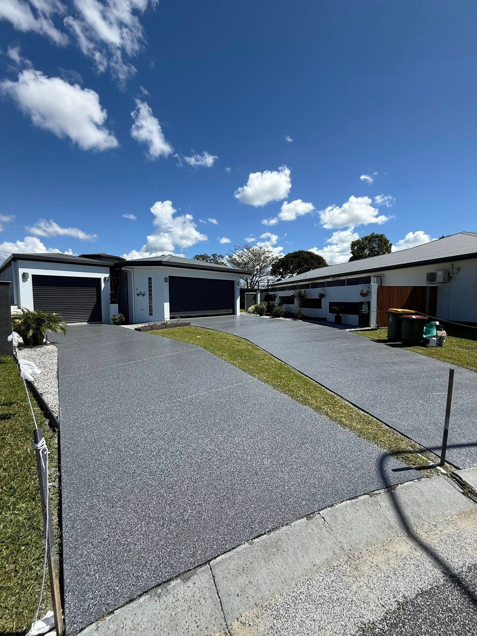 Gravel Driveway Leading to a Modern House and Garage Under a Bright Blue Sky — All Grind & Coat in Cairns, QLD