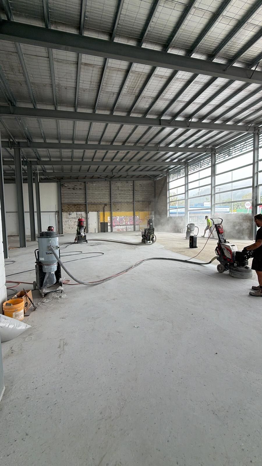 Workers Laying Concrete in a Large Steel-framed Warehouse Under Construction — All Grind & Coat in Cairns, QLD