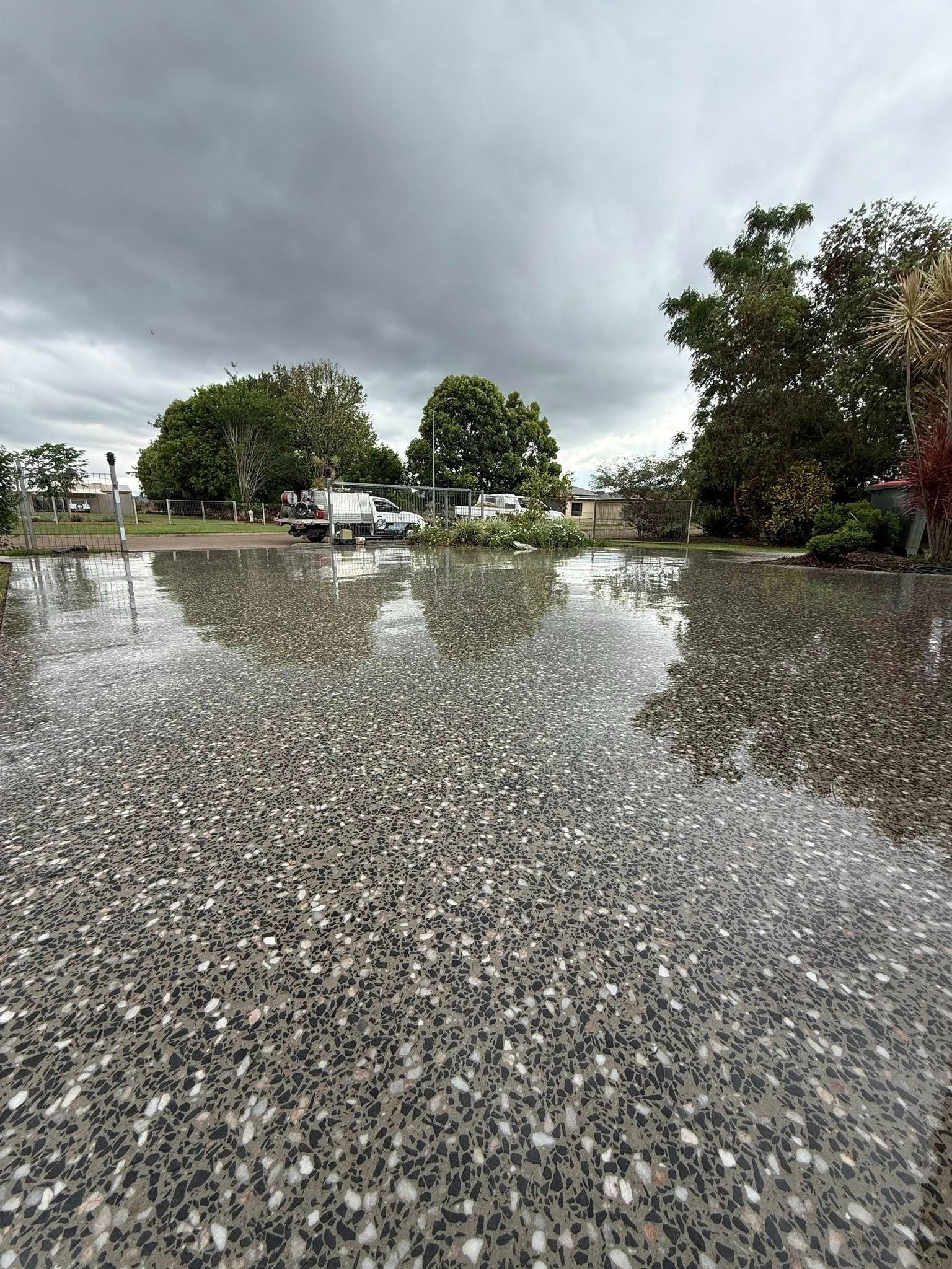 Wet polished concrete driveway with cloudy sky in background