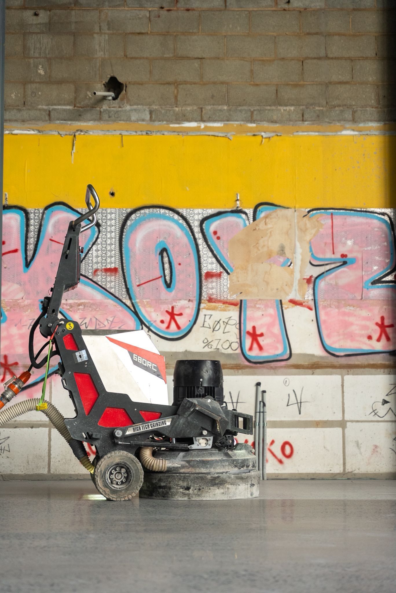 Person Grinding Concrete in front of Graffiti on a Brick Wall Indoors — All Grind & Coat in Cairns, QLD