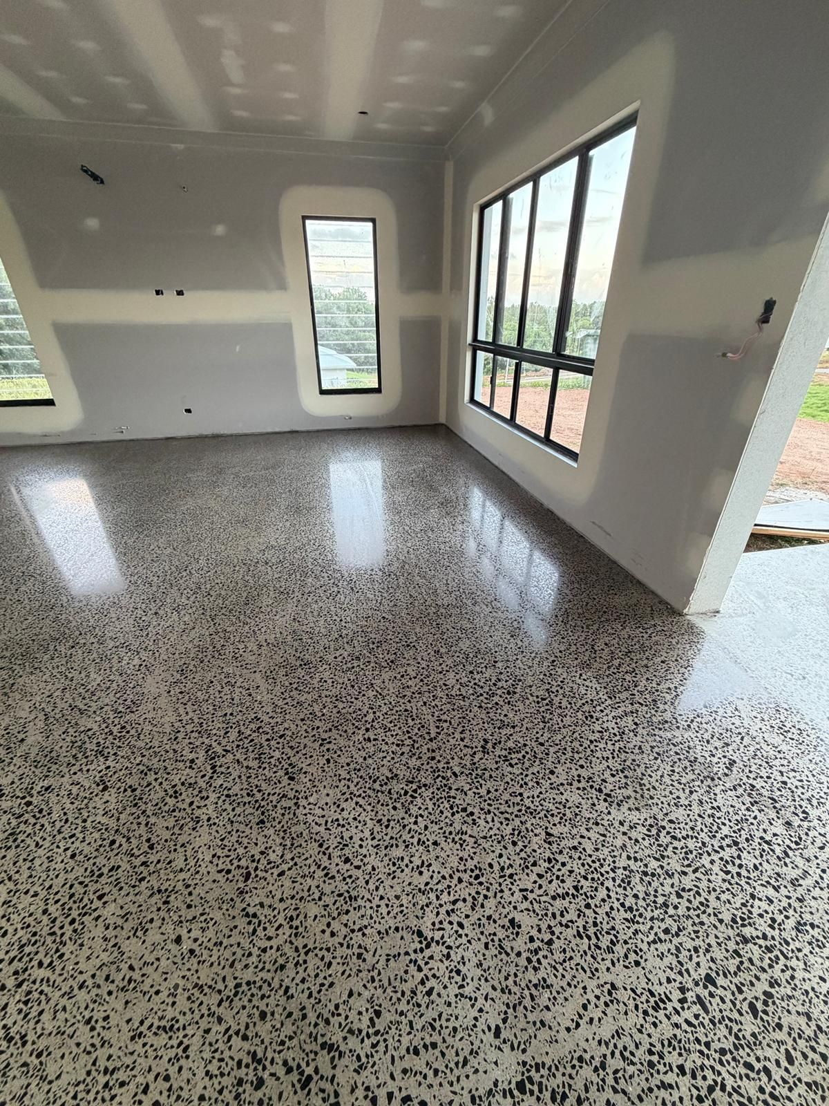 Empty Modern Room With Terrazzo Floor, White Walls, and Large Windows Letting in Daylight — All Grind & Coat in Cairns, QLD