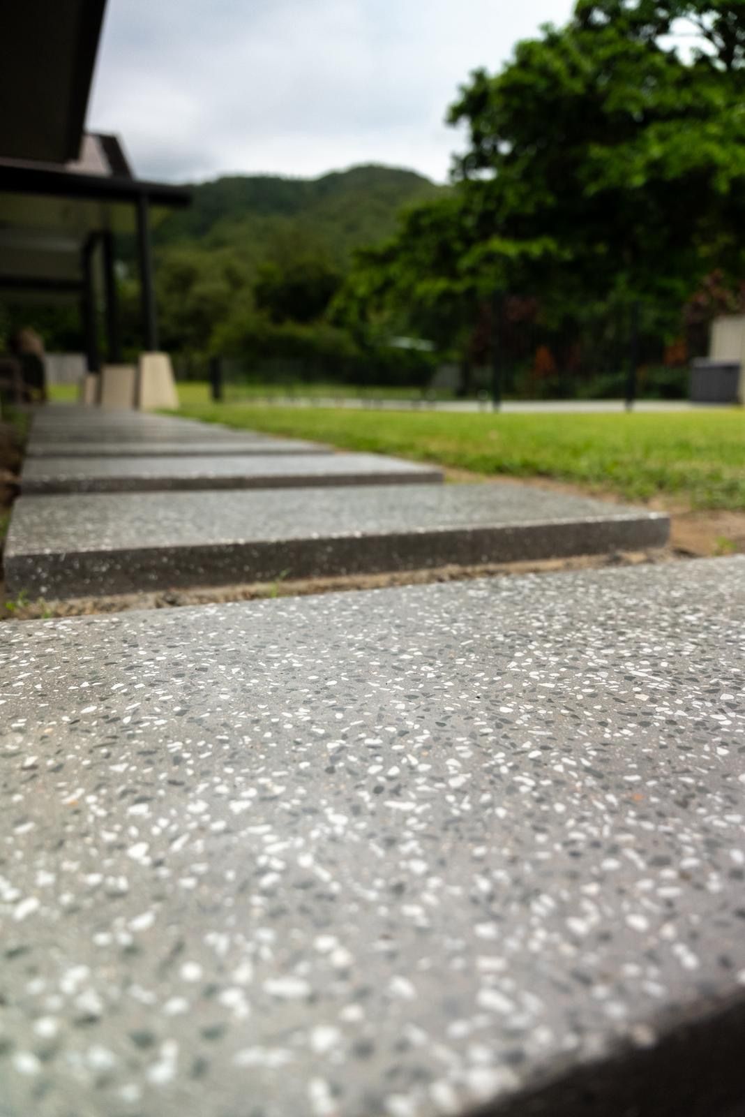 Low-angle View of a Stone Walkway Beside Grass and Trees in a Park-like Setting — All Grind & Coat in Cairns, QLD